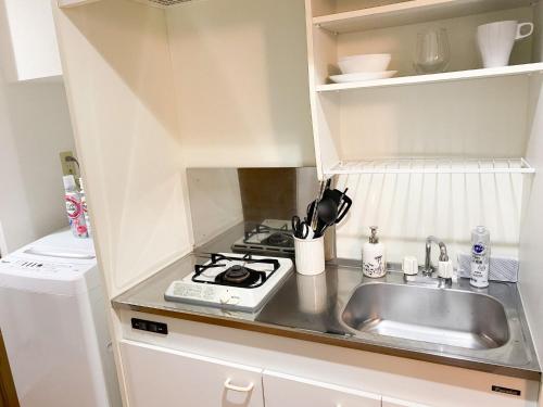 a small kitchen with a sink and a stove at Al Di La 四谷 in Tokyo