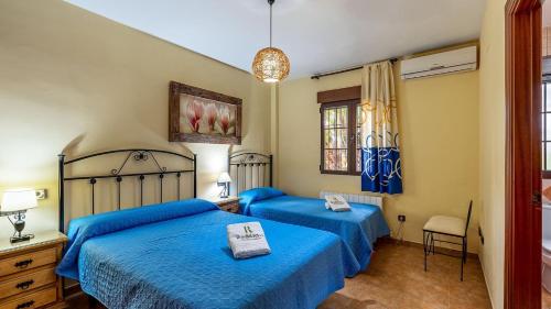 two beds in a bedroom with blue sheets at Cortijo Barranco Hondo Íllora by Ruralidays in Illora