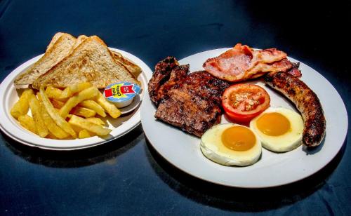 two plates of food with eggs bacon and french fries at SleepOver Kruger Gate in Skukuza
