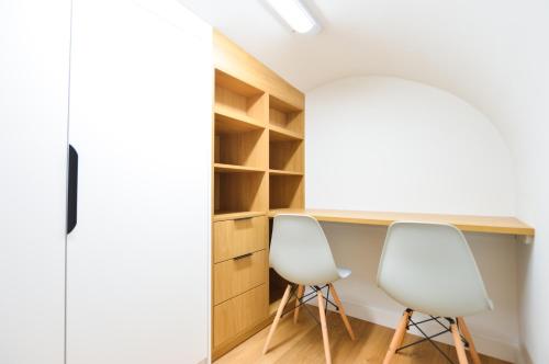 zwei weiße Stühle an einem Schreibtisch in einem Zimmer in der Unterkunft Sale Place Serviced Apartments by Concept Apartments in London