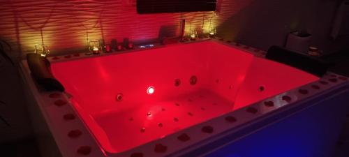 a red bath tub with lights in a room at Suite de charme avec JACUZZI illimité et jardin privatif in Saint-Prix