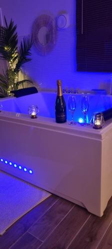 a white tub with two wine glasses and blue lights at Suite de charme avec JACUZZI illimité et jardin privatif in Saint-Prix