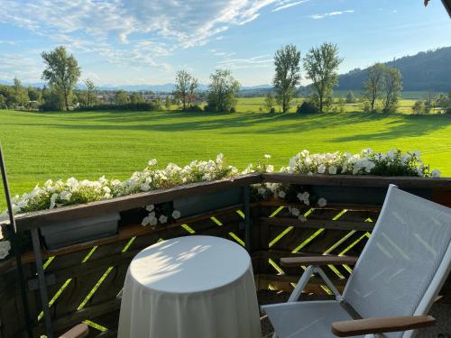 uma mesa e uma cadeira numa cerca com flores em Gemütliche Wohnung mit Ofen und Naturblick em Wildpoldsried