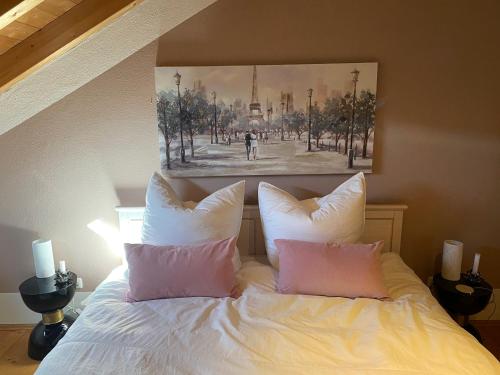 um quarto com uma cama com lençóis brancos e almofadas cor-de-rosa em Gemütliche Wohnung mit Ofen und Naturblick em Wildpoldsried