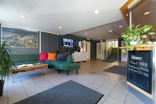 - un salon avec un canapé vert et une télévision dans l'établissement Kongsberg Hostel-Vandrerhjem, à Kongsberg