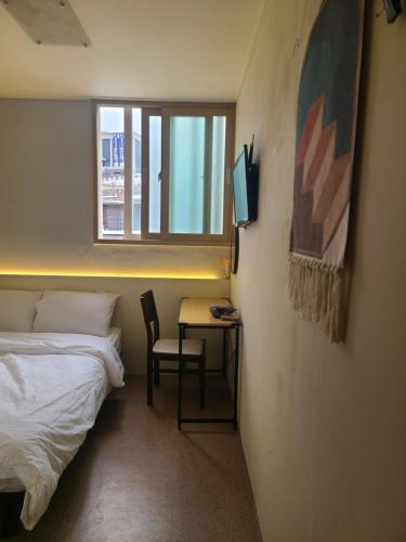 a bedroom with a bed and a desk with a television at Well Plus Guest House in Seoul