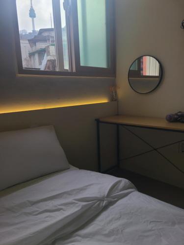 a bedroom with a bed and a mirror and a window at Well Plus Guest House in Seoul