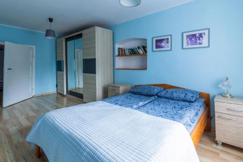 um quarto com uma cama e uma parede azul em Spękane Skały - Apartament em Miszkowice