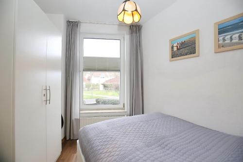 una camera bianca con un letto e una finestra di Sünnslag Wohnung 026EG a Boltenhagen