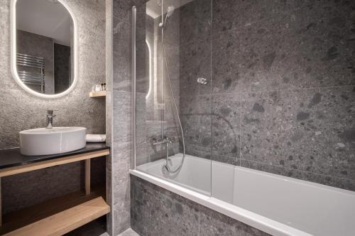 une salle de bain avec un lavabo, une baignoire et un miroir dans l'établissement Appartement Panorama, résidence Les Alpages, à Montvalezan