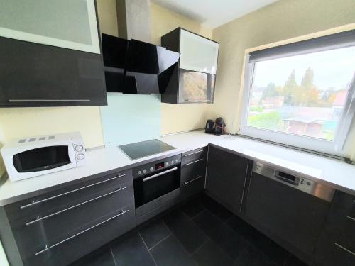 a kitchen with black cabinets and a microwave and a window at Pottmensch Oberhausen in Oberhausen