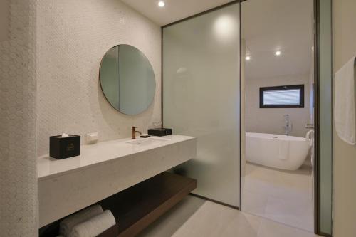 y baño con lavabo, espejo y bañera. en Hundert Hills en Jeju