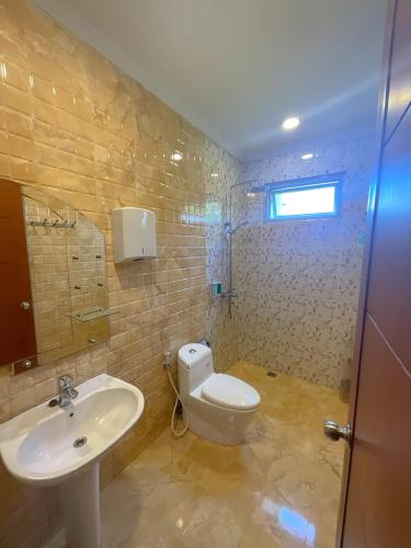 a bathroom with a white toilet and a sink at Villa London Puncak in Sampal 2
