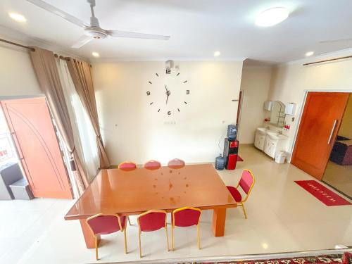 a dining room table with chairs and a clock on the wall at Villa London Puncak in Sampal 2