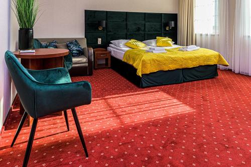 a bedroom with a bed and a table and a chair at Hotel Stara Gorzelnia in Licheń Stary