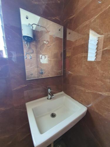 HOTEL DEO VOLENTE في Sibsāgar: حمام مع حوض أبيض ومرآة
