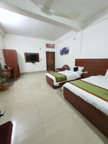 a hotel room with two beds and a flat screen tv at HOTEL DEO VOLENTE in Sivasagar