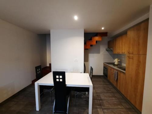 une petite cuisine avec une table et des chaises blanches dans l'établissement Charmante petite maison, à Cholet