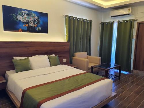 a bedroom with a large bed and green curtains at HOTEL DEO VOLENTE in Sivasagar