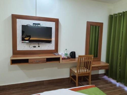 a living room with a tv and a chair at HOTEL DEO VOLENTE in Sivasagar