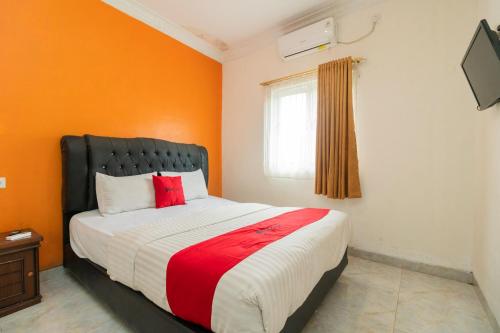 a bedroom with a bed with an orange wall at RedDoorz Syariah near Transmart Padang in Padang