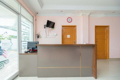 un bureau avec un bureau et une horloge sur le mur dans l'établissement RedDoorz Syariah near Transmart Padang, à Padang