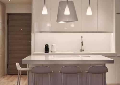 a kitchen with white cabinets and a sink and stools at Cute n Comfort Luxury Condo in Kolonaki in Athens