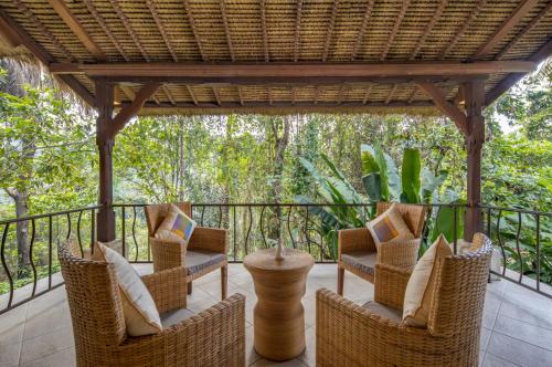 a porch with wicker chairs and a pergola at The Allure Ubud Villas & Spa crafted by freshWater Asia in Ubud