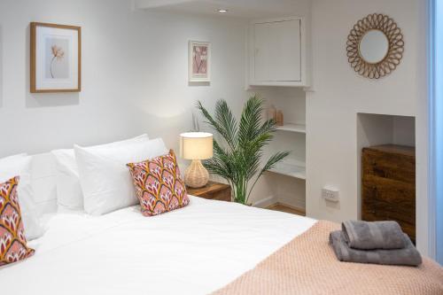 Bright & beautiful 4 bedroom house with sea views في بورتلاند: غرفة نوم بسرير ابيض ومخدات وزرع