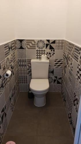 La salle de bains est pourvue de toilettes et d'un mur carrelé. dans l'établissement Maison au calme et proximité plage., à Saint-Quay-Portrieux