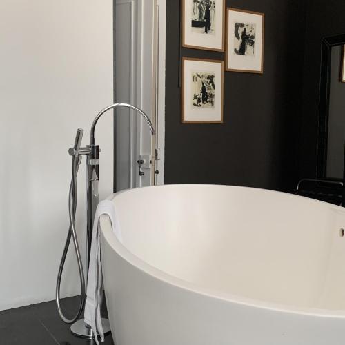 a bath tub in a bathroom with pictures on the wall at Hôtel Particulier Le 28 - Spa & Art Luxury Design by Alain Ducasse in Aix-en-Provence
