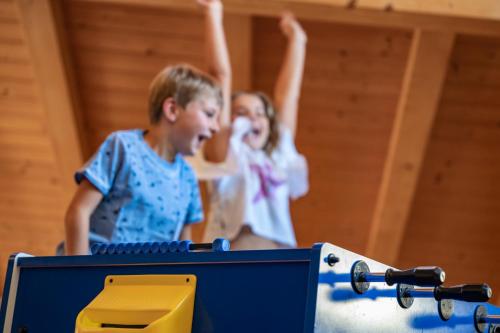 two children are playing with a table with a machine at Hotel Spitaler in Appiano sulla Strada del Vino