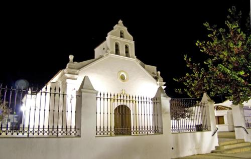 a white church behind a fence at night at Hotel Rural El Arriero in La Zarza