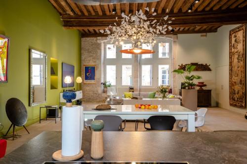 un salon avec une table et un lustre dans l'établissement Côté Paradis - Appartements de Charme au centre-ville de Beaune, à Beaune