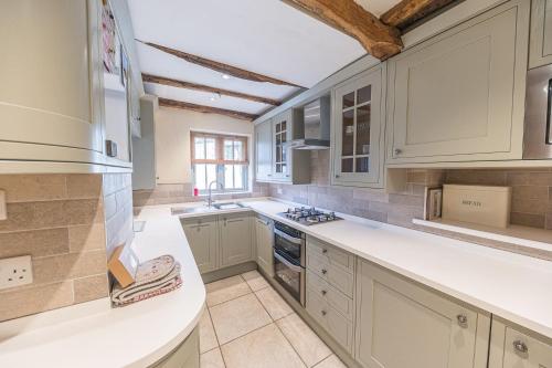 a kitchen with white cabinets and a sink at 2 Dixon Ground Coniston in Coniston