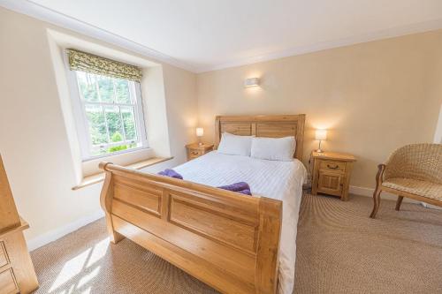 a bedroom with a bed and a chair and a window at 2 Dixon Ground Coniston in Coniston