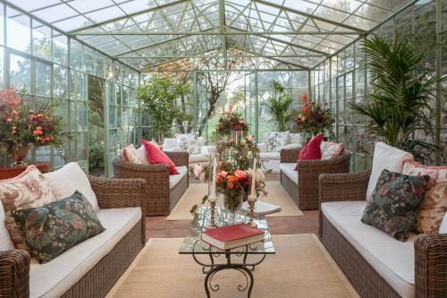 a conservatory with couches and tables and plants at Il Borgo di Vescine in Radda in Chianti