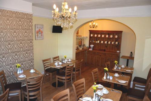 a restaurant with wooden tables and chairs and a chandelier at Ashlea Guest House in Banbury