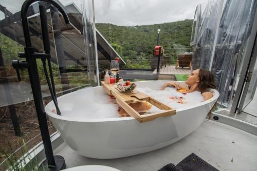 a woman laying in a bath tub on a balcony at Stargazing Dome - Thunzi Bush Lodge in Beachview
