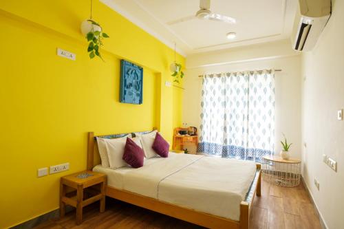 a bedroom with a bed with yellow walls and a window at Moustache Hostel, Jaipur in Jaipur