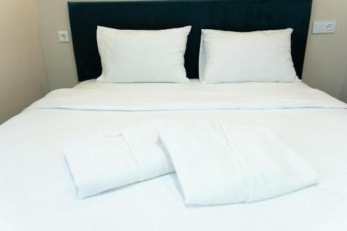 a white bed with white pillows and white sheets at Jardin in Aktobe