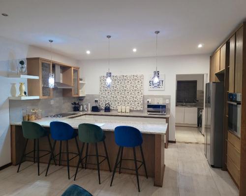 a kitchen with a island with blue bar stools at Sebs Chalet in Hartbeespoort