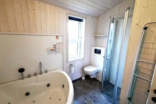 uma casa de banho com uma banheira, um WC e um chuveiro em Kapitänshus-Strandpark 24 em Grömitz