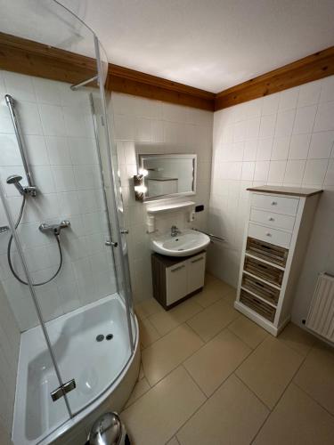 a bathroom with a shower and a sink and a tub at Brenners Dorfstube in Fieberbrunn