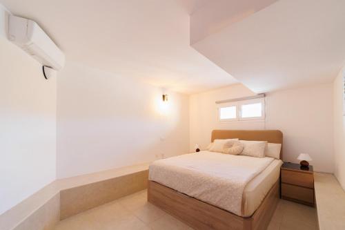 a white bedroom with a bed and a window at Moser Living Premium Apartments in Mogán