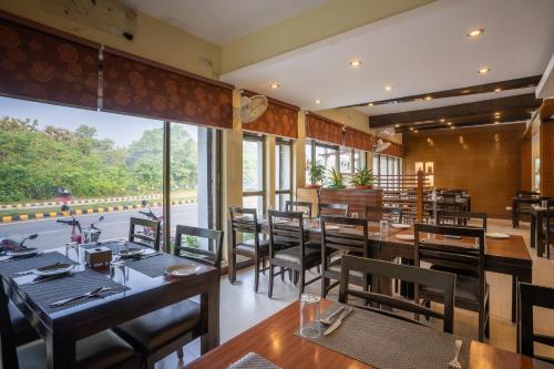a restaurant with wooden tables and chairs and a large window at Hotel Peaceland Lumbini in Lumbini
