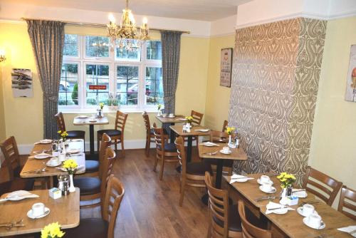 a restaurant with wooden tables and chairs and a window at Ashlea Guest House in Banbury
