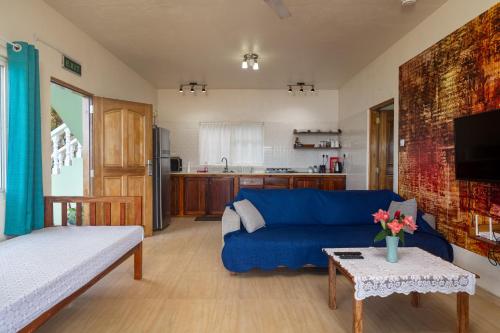 a living room with a blue couch and a kitchen at TOP VIEW RETREAT SELFCATERING in Anse a La Mouche