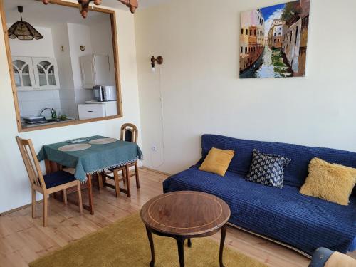 a living room with a blue couch and a table at Sylvis Place in Gödöllő