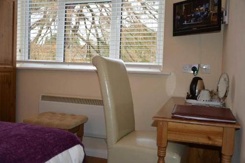 a bedroom with a desk with a chair and a window at Ashlea Guest House in Banbury